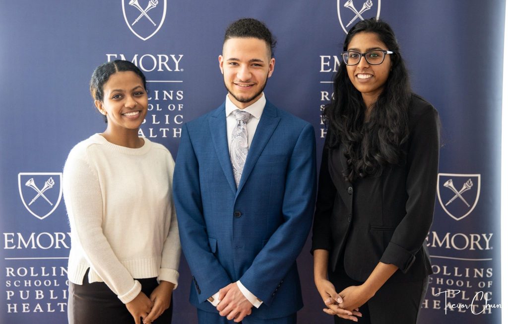 Three UMBC students in professional attire pose together at a public health conference event.